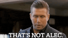 a man in a suit is standing in front of a sign that says `` that 's not alec '' .