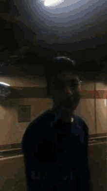 a man in a blue sweater is standing in front of a sign that says no smoking