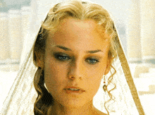 a woman wearing a veil and earrings looks at the camera