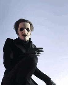 a man in a mask and gloves is standing in front of a blue sky and making a funny face .