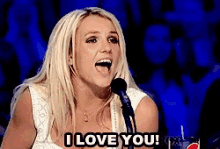 a blonde woman singing into a microphone with the words i love you on the bottom