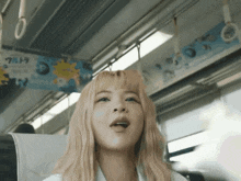 a woman with blonde hair is sitting on a bus with a sign that says ultra