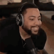 a man with a beard wearing headphones and a microphone is smiling .