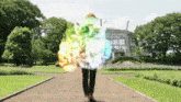 a person standing in a park with a rainbow of colors coming out of them
