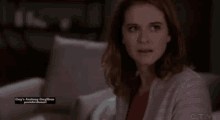 a woman is sitting on a couch with a grey 's anatomy logo on the bottom