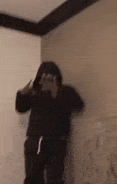 a person in a black hoodie is standing in a room .