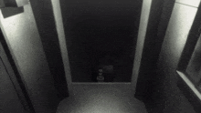 a black and white photo of a dark hallway with a light shining on the door