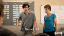 a man and a woman are standing in front of a board that says we 're done .