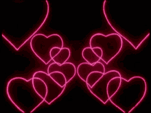 a bunch of pink neon hearts on a black background .