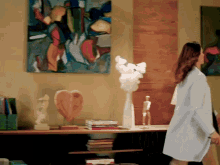a woman in a white shirt stands in front of a painting