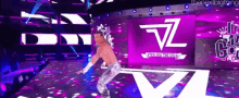 a man is dancing on a stage in front of a large screen that says vz