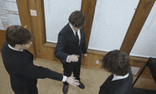 a man in a suit and tie is standing in a room with two other men