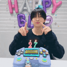 a man is sitting in front of a birthday cake with the number 27 written on it