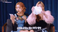 two girls are sitting on a couch and one is wearing a shirt that says tap on it