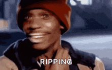 a man wearing a red beanie is smiling and the word ripping is on his face
