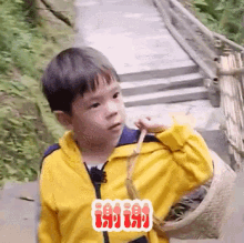 a young boy wearing a yellow jacket is holding a basket and making a funny face .