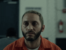 a man with a beard is wearing an orange uniform