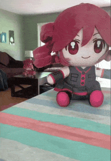 a stuffed doll with red hair is sitting on a striped blanket