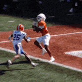 a football player with the number 25 on his jersey is trying to catch the ball