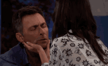 a woman touches a man 's face with her hand while he has his eyes closed