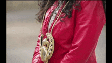 a woman in a red leather jacket has a gold necklace around her neck