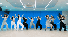 a group of women are dancing in front of a blue wall and one of them has the word bad on her shirt