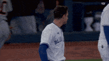 a baseball player wearing a blue jays jersey stands on the field