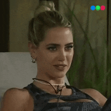 a woman wearing a necklace and earrings sits on a chair