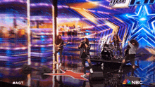 a band is performing on a stage with a nbc logo in the background