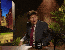 a man in a suit and tie is sitting at a table with a mug that says af