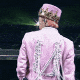 a man wearing a pink jacket and a crown is standing on a stage .