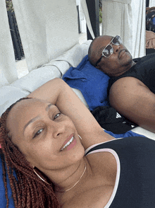 a man and a woman are laying on a couch and the man is wearing sunglasses