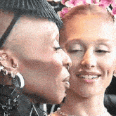 a woman with a shaved head is kissing another woman on the forehead .