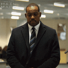 a man in a suit and tie is standing in front of a sign that says project hail mary