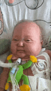 a baby is laying in a hospital bed with an oxygen tube around his neck