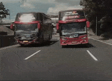 two buses are driving down a highway and one of them has a sticker on the front that says ' pacific jaya '