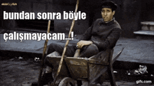 a man is sitting in a wheelbarrow with a broom and the words " bundan sonra böyle çalışmayacam ! "