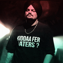a man in a turban is wearing a black shirt that says kiddaa fer haters