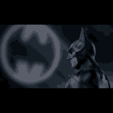 a man in a batman costume stands in front of the batman logo