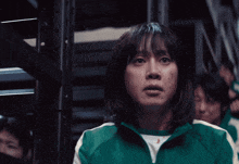 a woman in a green shirt is standing in a dark room with other people