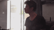 a man in a black shirt is sitting in front of a window