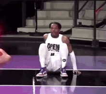 a basketball player wearing a white jersey that says open sits on the court .