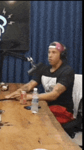 a man wearing headphones is sitting at a table with a bottle of water