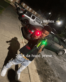 a young man is holding a green laser gun and says reflex 2024 da hood prime on the bottom