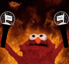 elmo from sesame street is holding a pair of microphone in front of flames