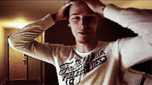 a young man wearing a shirt that says freak on it is holding his head