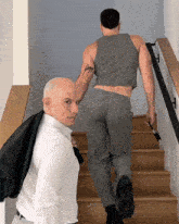 a man with a tattoo on his arm is walking down the stairs next to another man