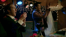 a man in a suit and tie applauds another man
