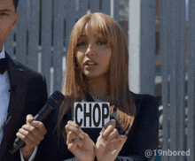 a woman holds a sign that says chop in front of a microphone