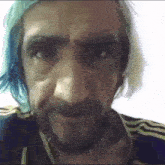 a man with a beard and blue hair is looking at the camera
